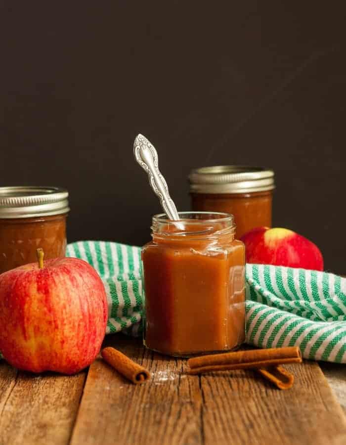 jars of slow cooker apple butter with apples and cinnamon sticks