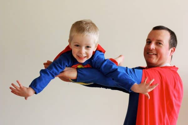 a father in a superman costume holding a child in a superman costume