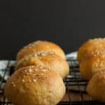 whole wheat hamburger buns on a baking rack against a black background