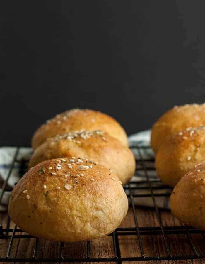 whole wheat hamburger buns on a baking rack against a black background