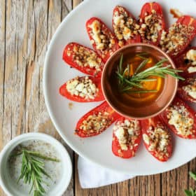 feta stuffed grilled tomatoes on a plate with olive oil and herbs