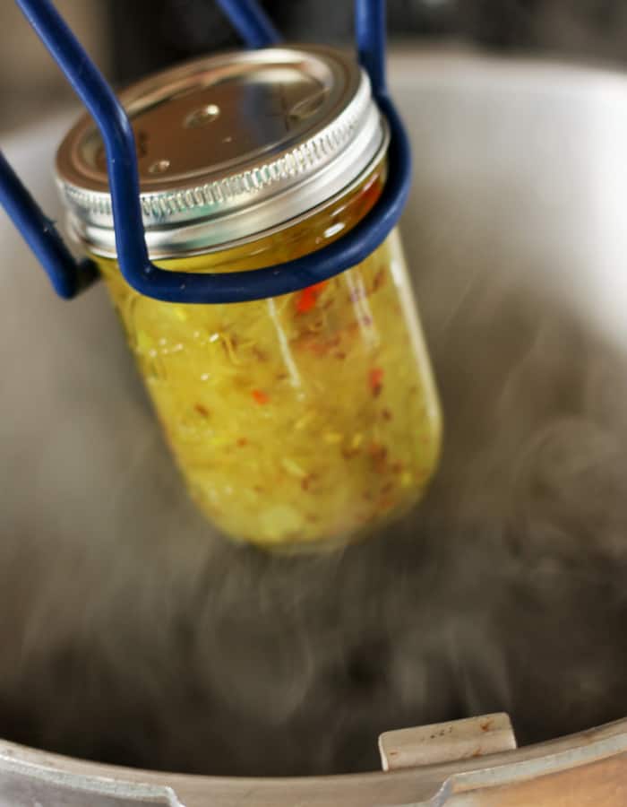 canning tongs putting dill relish into a water canner