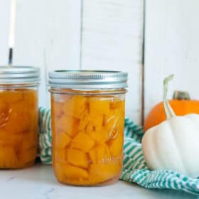 Two jars of canned pumpkin with mini pumpkins