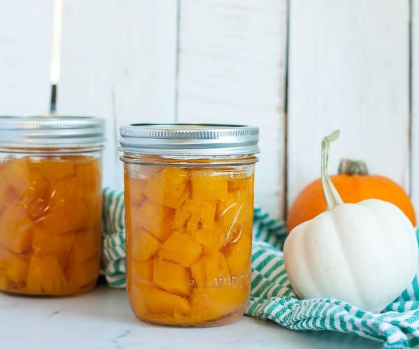 Two jars of canned pumpkin with mini pumpkins