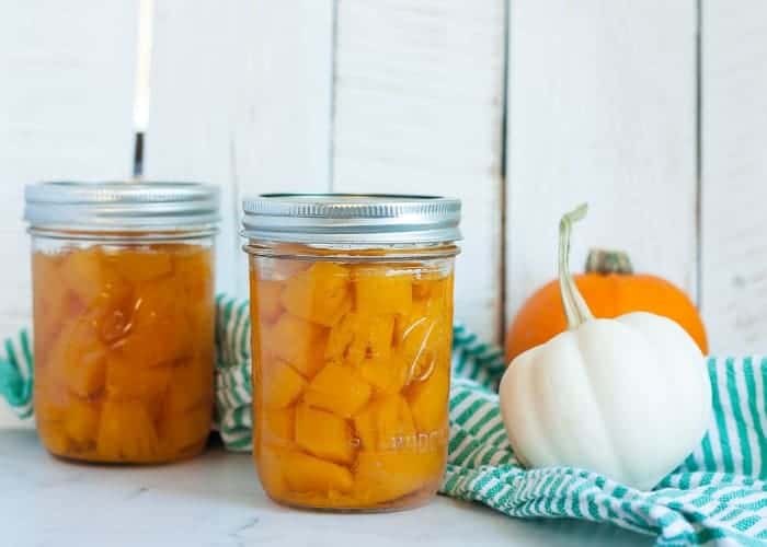 Two jars of canned pumpkin with mini pumpkins