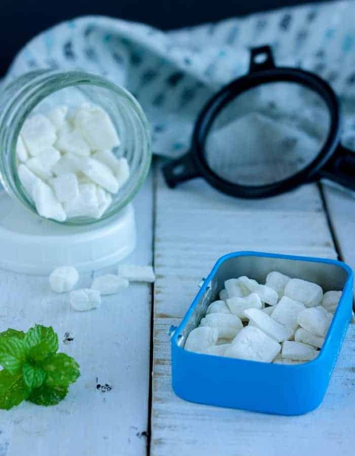 homemade mints in two containers with a small black strainer