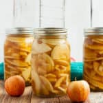 three jars from canning apple pie filling on a wooden board