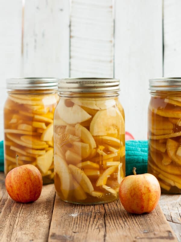 three jars from canning apple pie filling on a wooden board