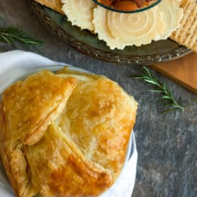 baked brie in puff pastry with a plate of crackers and rosemary