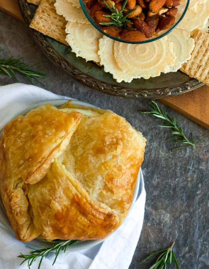 baked brie in puff pastry with a plate of crackers and rosemary