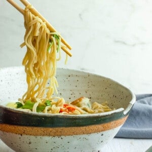 chopsticks holding noodles over homemade ramen noodle bowls