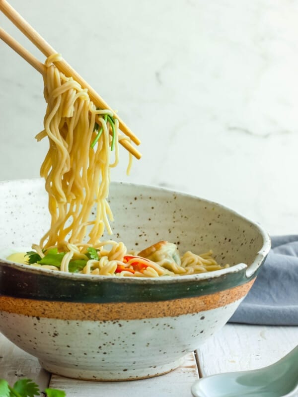 chopsticks holding noodles over homemade ramen noodle bowls