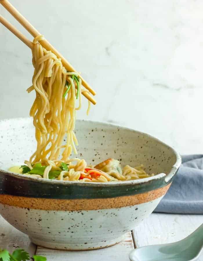 chopsticks holding noodles over homemade ramen noodle bowls