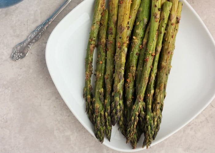 roasted asparagus on a white plate with a fork