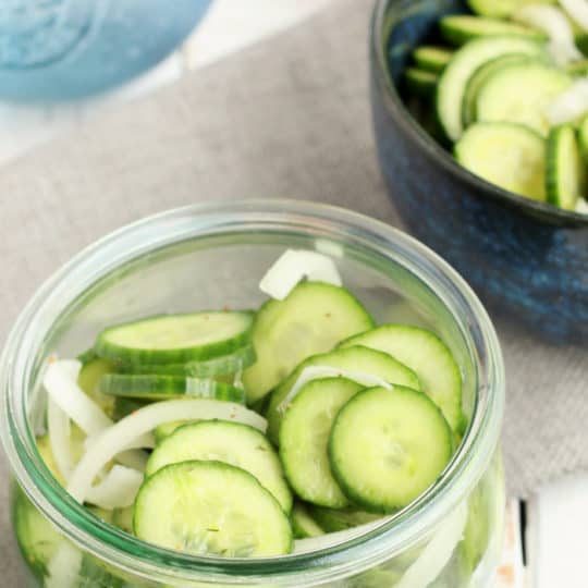 two bowls of cucumber and onion salad on a gray cloth