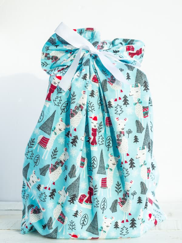 a blue fabric gift bag with holiday llamas