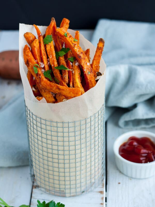 A stack of sweet potato fries topped with salt and parsley
