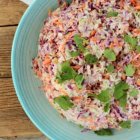 A bowl of spicy easy coleslaw in a blue bowl on a wooden board
