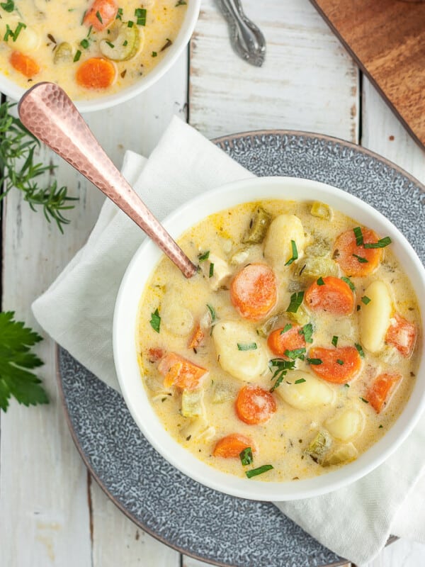 a bowl of chicken gnocchi soup on a grey plate with a white napkin