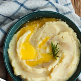 An easy mashed potato recipe in a bowl topped with butter and rosemary
