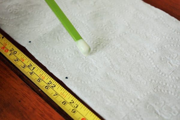 a chop stick with paste on it marking spots on toilet paper for seed tape