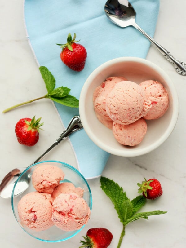 two bowls of homemade strawberry ice cream with mint and whole strawberries