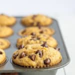 a muffin tray with a fluffy healthy banana chocolate chip muffin in focus