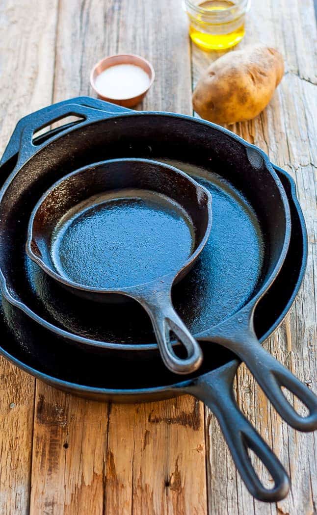 3 stacked cast iron skillets with onion, salt, and a potato