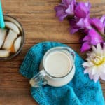 sugar-free coffee creamer in a pitcher on a blue cloth with flowers and iced coffee