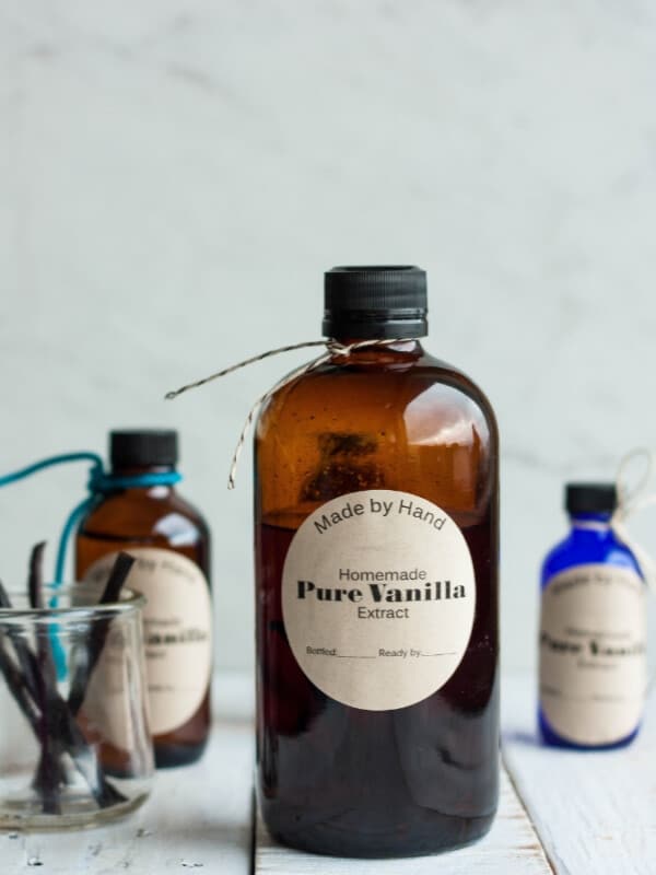 three bottles of homemade vanilla extract with a dish of vanilla beans