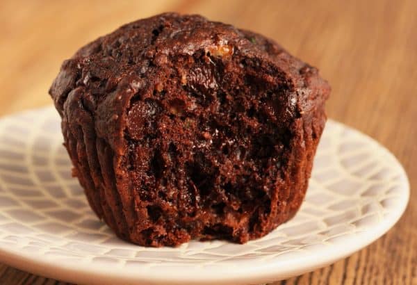 double chocolate zucchini muffin with a bite out of it on a plate