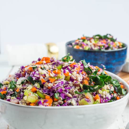 a white and blue bowl full of kale chopped salad