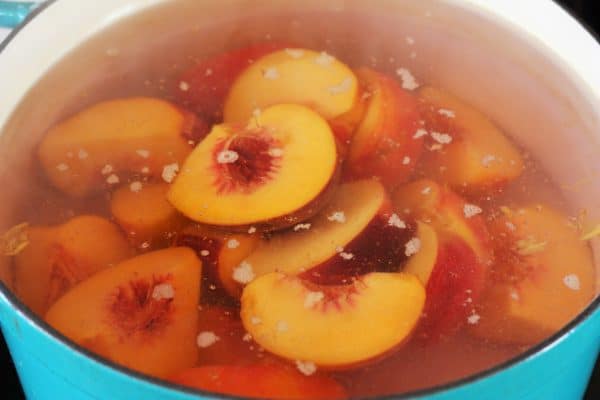 sliced peaches in a teal stockpot.