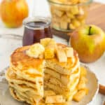 A stack of healthy apple pie pancakes with a slice cut out