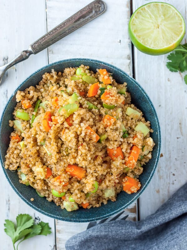 a bowl of instant pot quinoa with veggies on a white board with lime and cilantro