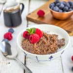 a white bowl of chocolate quinoa topped with berries
