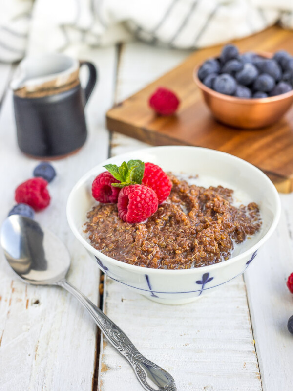 a white bowl of chocolate quinoa topped with berries