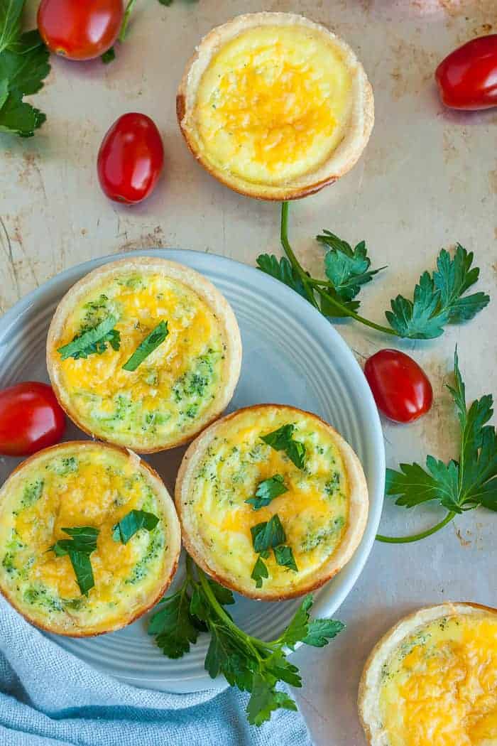muffin tin quiche on a plate with tomatoes and parsley