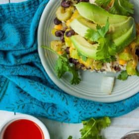 a plate of leftover turkey casserole on a blue cloth with avocado and hot sauce