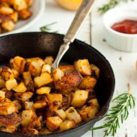 skillet fried potatoes in a cast iron skillet with rosemary and ketchup