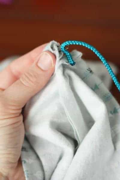 hands threading a blue rope through fabric to make a drawstring