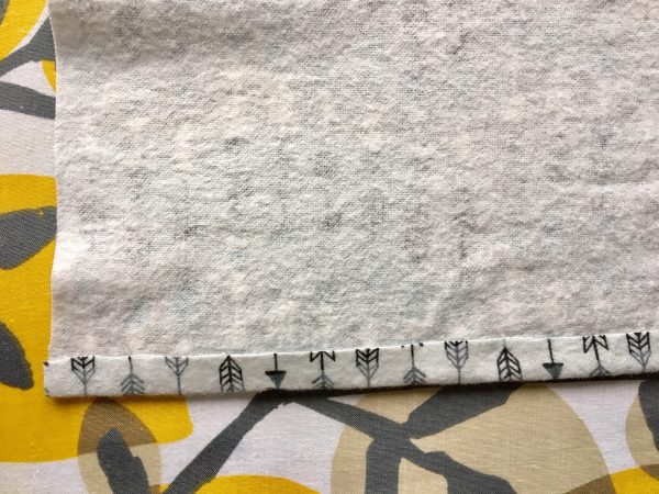 a folded piece of cloth with arrows on a floral ironing board