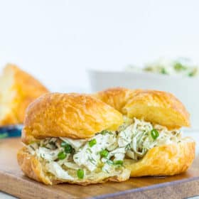 Dill chicken salad on a crossiant on a wooden board