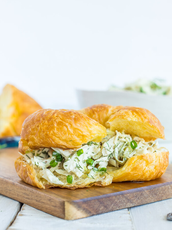 Dill chicken salad on a crossiant on a wooden board