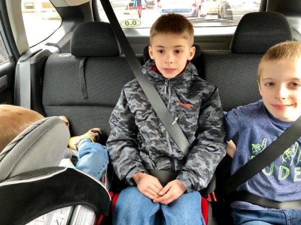 three kids in the backseat of a car