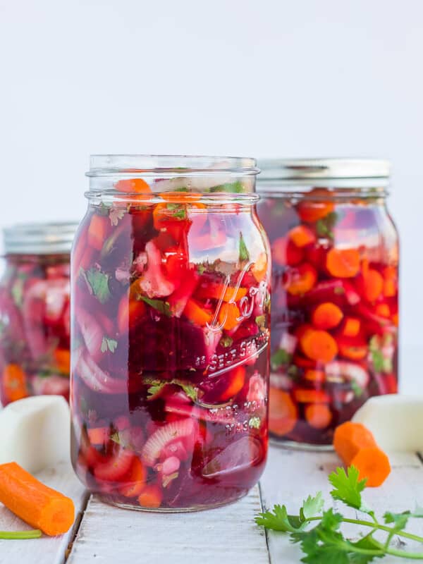 3 jars of pickled encurtido and vegetables on a white board