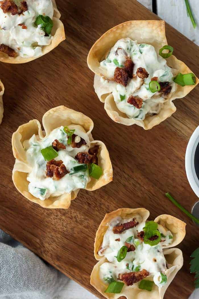 three jalapeno popper wontons on a wooden cutting board