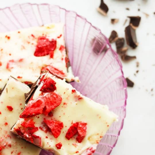 A pink plate with strawberry and chocolate bark