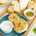 Instant Pot roasted garlic on a blue plate with a dish of salt