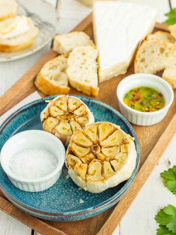 Instant Pot roasted garlic on a blue plate with a dish of salt